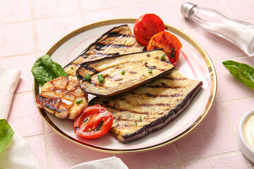 Plate with delicious grilled eggplants, tomatoes and garlic on pink background