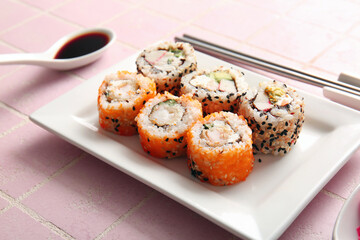 Plate with tasty sushi rolls on table,  closeup