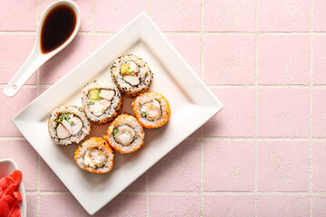 Plate with tasty sushi rolls and soy sauce on table, top view