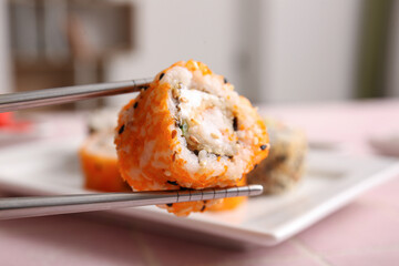 Chopsticks with tasty sushi roll, closeup view