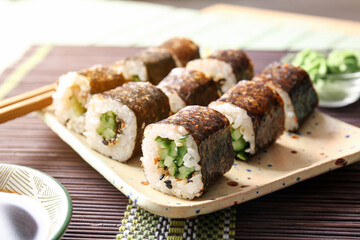 Plate with tasty maki rolls on table, closeup
