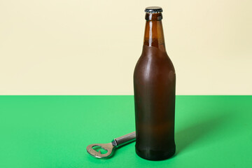 Bottle of cold beer and opener on color background