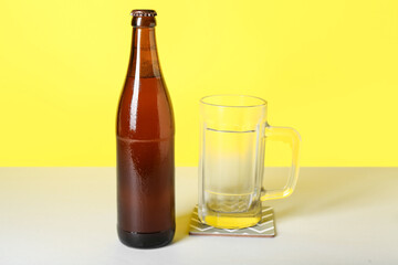 Bottle of cold beer and mug on color background