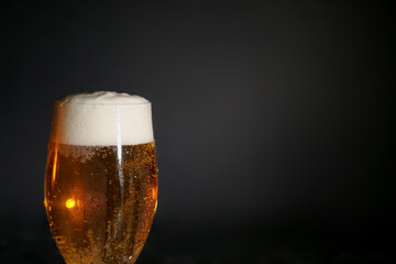 Glass of cold beer on dark background, closeup