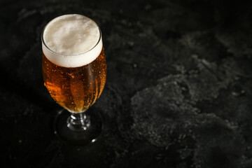 Glass of cold beer on dark background