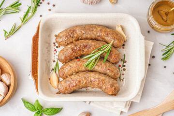 Baking dish of tasty homemade sausages on grey background