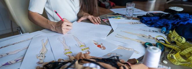Faceless woman draws sketches of swimwear with a pencil. Close-up of the hands of a fashion designer.