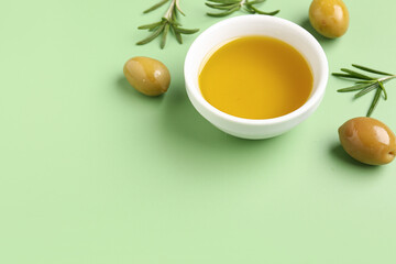 Bowl with fresh olive oil on green background