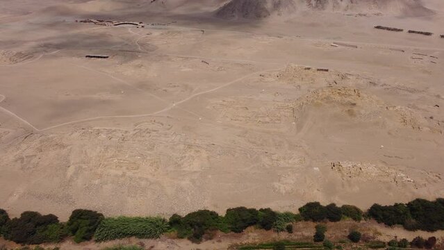 Aerial video of the ancient temple city of Caral. One of the oldest cities of the world. Drone hovers and pans left above the archaeological site. Located in the Supe valley of Lima, Peru.
