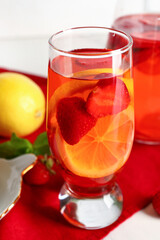 Glass and jug of infused water with strawberry and lemon, closeup
