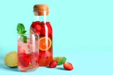 Glass and bottle of infused water with strawberry on blue background