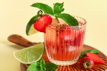 Glass of infused water with strawberry and lime on yellow background