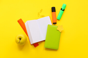 Fresh apple with different stationery on yellow background