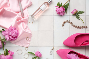 Frame made of stylish female accessories, high heels, cosmetics and peony flowers on light tile background