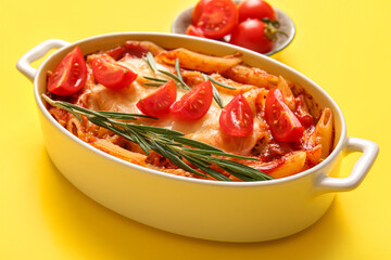 Baking dish of pasta with tomato sauce and cheese on yellow background
