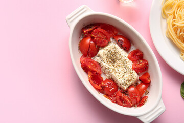 Baking dish with tasty tomatoes and feta cheese on pink background