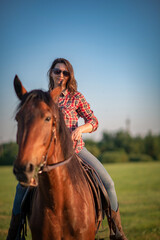 Obraz premium Portrait of a young beautiful girl with a horse on a ranch in a field.