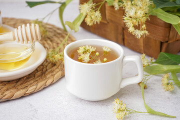 Cup of linden tea and bowl with honey on white table
