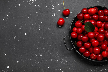 Plate with sweet cherries on black background
