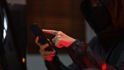 Hacker in hoodie using smartphone and computer to hacking programming system or data of server