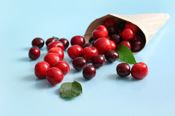 Newspaper with sweet cherries on blue background