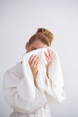 The girl wipes her face with a terry towel.