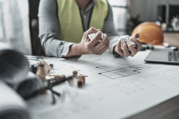 The architect, engineer made a mistake in designing the plan. Paper crump blueprint in hand. Fail, mistake and problem concept.
