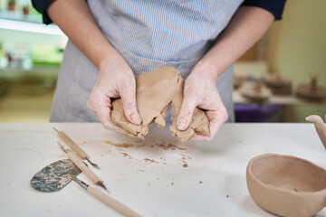 Closeup hands of ceramic artist wedging clay in art studio