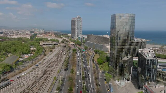 Transport infrastructure in city. Aerial view of busy multilane road and multitrack railway line leading along sea coast in urban borough. Barcelona, Spain