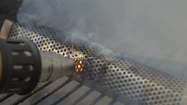 This video shows a heat gun setting a pellet smoker on fire as smoke pours over the grill.