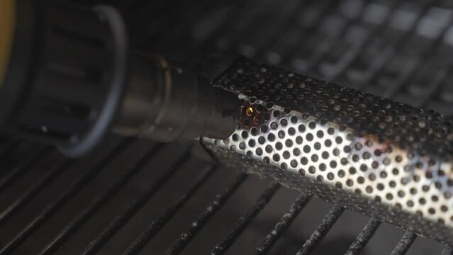 This close up video shows heat gun torch igniting a pellet tube smoker in a grill.