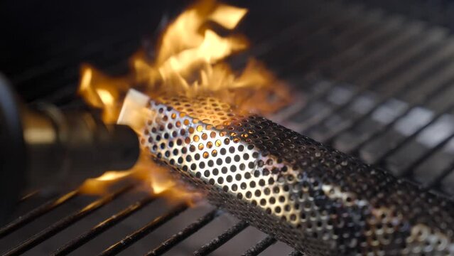 This slow motion video shows a close up view of a heat gun torch setting a pellet smoker tube on fire.