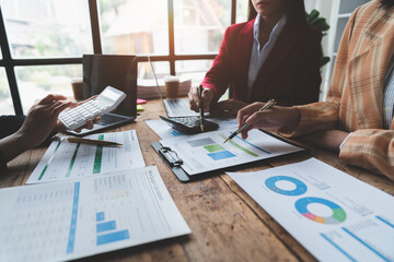 Businesswoman teamwork discussing brainstorming and calculating with calculator on evaluation data in conference room Focus on business growth and point out financial accounting charts.
