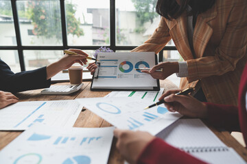 Businesswoman teamwork, discussing, brainstorming, pointing to earnings, income, taxes data in conference room. Focus on business growth and point out financial accounting charts.