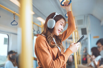 Happy young Asian woman passenger listening music via smart mobile phone in a train, Smile female...
