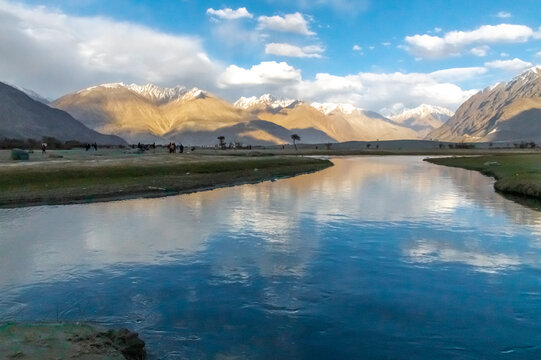 Hunder village in the Leh Nubra valley of Ladakh is famous for Sand dunes, Bactrian camels. Evening view of river and hills with dramatic clouds.