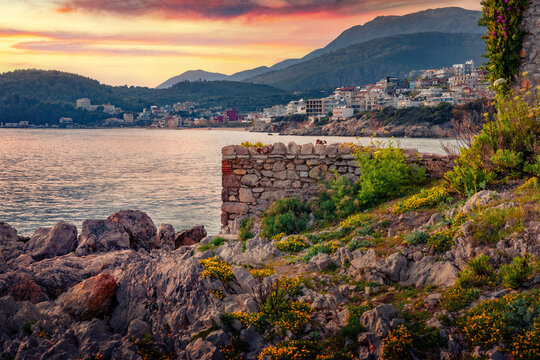 Blooming flowers on the shore of Adriatic sea in Himare town. Amazing sunset in Albania, Europe. Traveling concept background.
