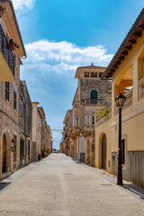 Fototapeta na wymiar An idyllic scene of small village Petra old town, an empty narrow street lined with old facades, preserving the timeless charm of this Mediterranean gem. Balearic Islands Spain.