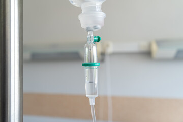 Infusion bag with drop counter on a IV stand pole or bottle hanger. Intravenous therapy, hanging bag of medicine for a patient receiving fluids through an intravenous line in a hospital room.