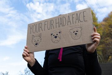 Woman holding placard sign with text Your fur had a face, during animals rights march. Female...