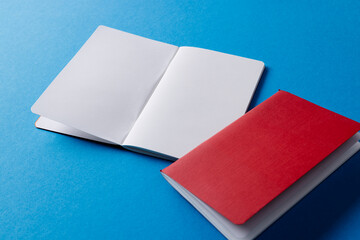 Close up of red notebook and open book with copy space on blue background