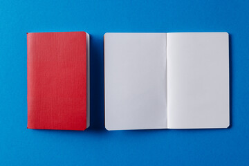 Close up of red notebook and open book with copy space on blue background