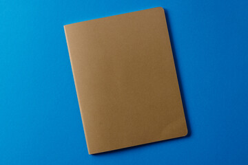 Close up of beige notebook with copy space on blue background