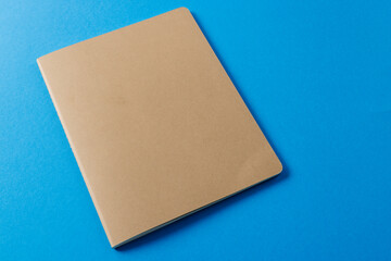 Close up of beige notebook with copy space on blue background