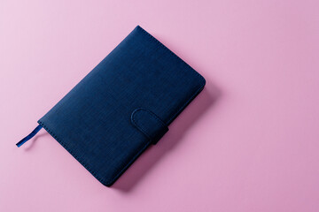 Close up of blue notebook with copy space on pink background