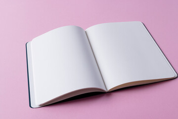 Close up of open book with copy space on pink background