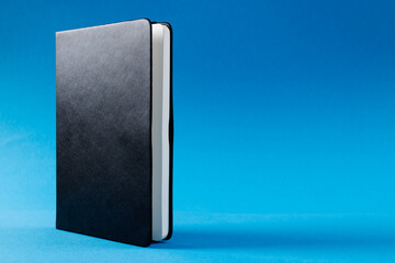 Close up of black notebook with copy space on blue background