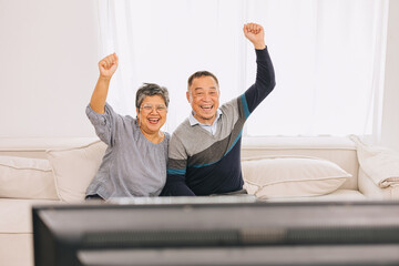 Senior eldely asian family old man and woman enjoy happy watching tv holiday activity together at...