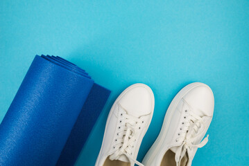 Top view photo of white sneakers and fitness mat.