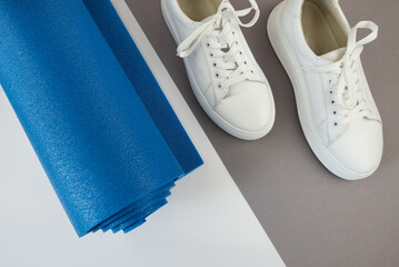 Top view photo of white sneakers and fitness mat.